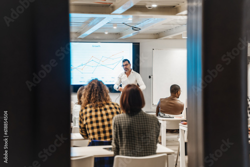 Good looking middle-aged business trainer sharing knowledge and guidance to a group of young multiracial employees for better efficiency at the work
