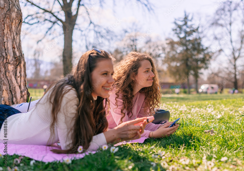 Beautiful girls looking at something funny and smiling while enjoying sunny day at the park Beautiful girls looking at something funny and smiling while enjoying sunny day at the park