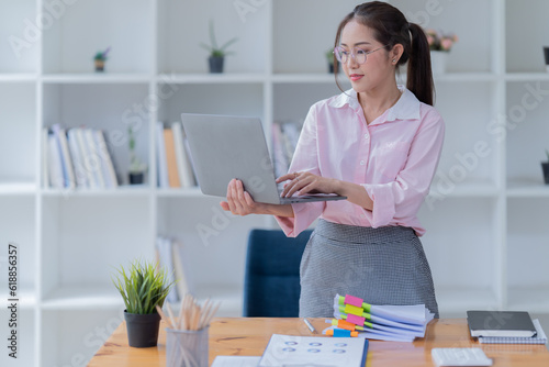 Sharing good business news. Attractive young businesswoman talking on the mobile phone and smiling while sitting at her working place in office. © Tj