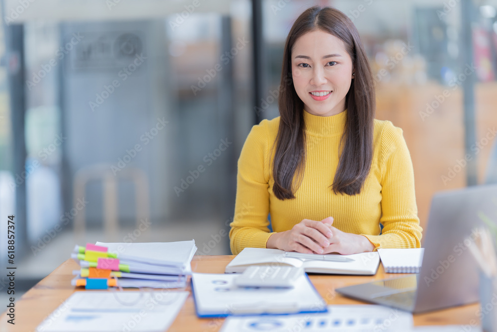 Attractive young office worker holding a binder as she looks at the camera with a sweet friendly smile Attractive young office worker holding a binder as she looks at the camera with a sweet friendly smile