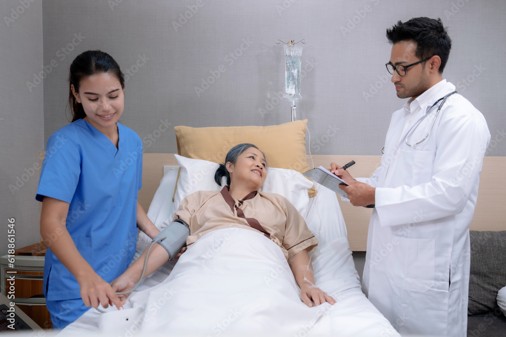 Elderly Asian woman is being treated at a hospital under close supervision of doctors and nurses. Elderly Asian woman is being treated at a hospital under close supervision of doctors and nurses.