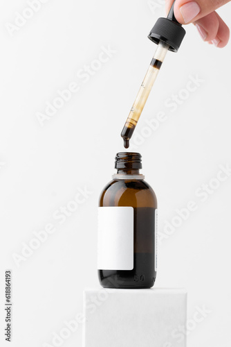 Картината върху платно Woman dripping medical iodine from pipette into glass bottle on the white background