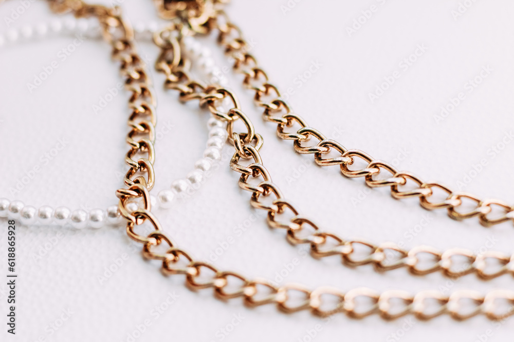 A necklace of white beads with chains of jewelry on a white aesthetic background. A necklace of white beads with chains of jewelry on a white aesthetic background.