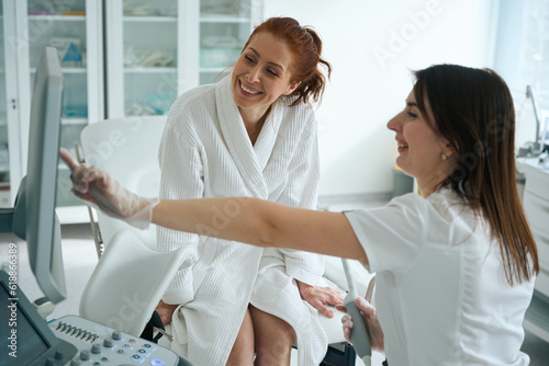 Female gynecologist showing to female patient ultrasound image on screen photo