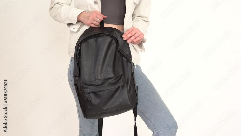 The model demonstrates a backpack. Girl holding and demonstrate his new black leather backpack The model demonstrates a backpack. Girl holding and demonstrate his new black leather backpack