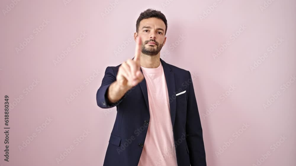 Young hispanic man business worker with serious face saying no with finger over isolated pink background Young hispanic man business worker with serious face saying no with finger over isolated pink background