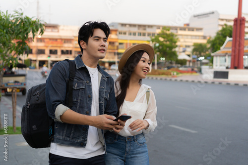 Happy smiling Young Asian couple traveler tourists hailing for taxi cab on the street in Bangkok in Thailand with no phone or use of technology © twinsterphoto