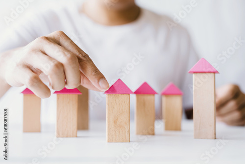 Hands of young man assembling house model from wooden blocks, village construction concept from wooden blocks and planning concept saving money to buy a house
