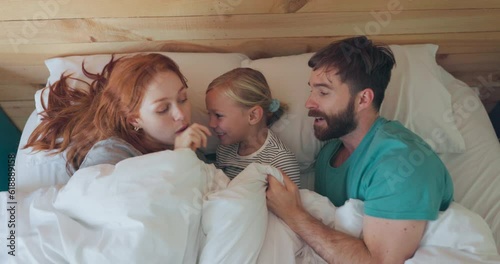 Happy, comfy and above of a family in bed for love, care or bonding together at night. Smile, talking and a mother, father and child in the bedroom with a blanket for comfort and to relax in a house photo