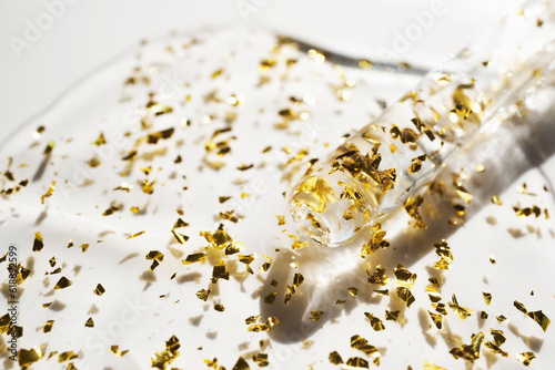 Pipette and drop of cosmetic product with gold particles, selective focus photo