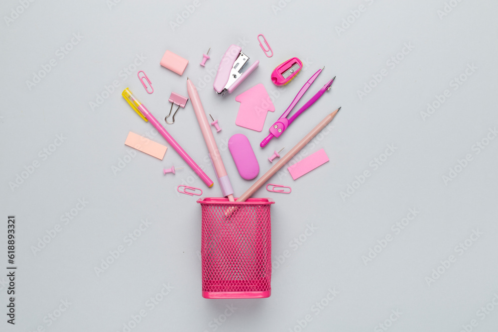 Pink pencil holder with school stationery on color backgroung, top view