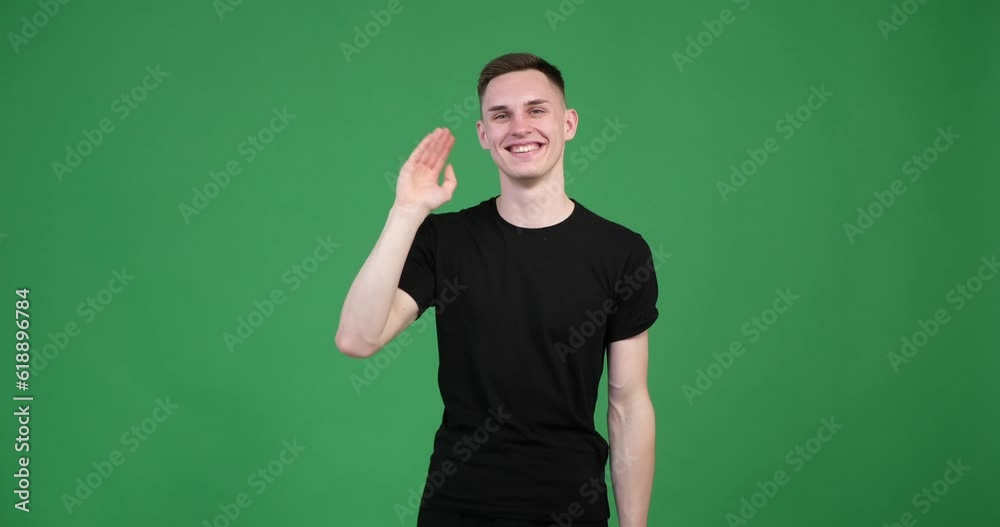 Smiling Caucasian man on a vibrant green screen background. With a warm and friendly expression, he is depicted waving his hand in a cheerful greeting. Smiling Caucasian man on a vibrant green screen background. With a warm and friendly expression, he is depicted waving his hand in a cheerful greeting.