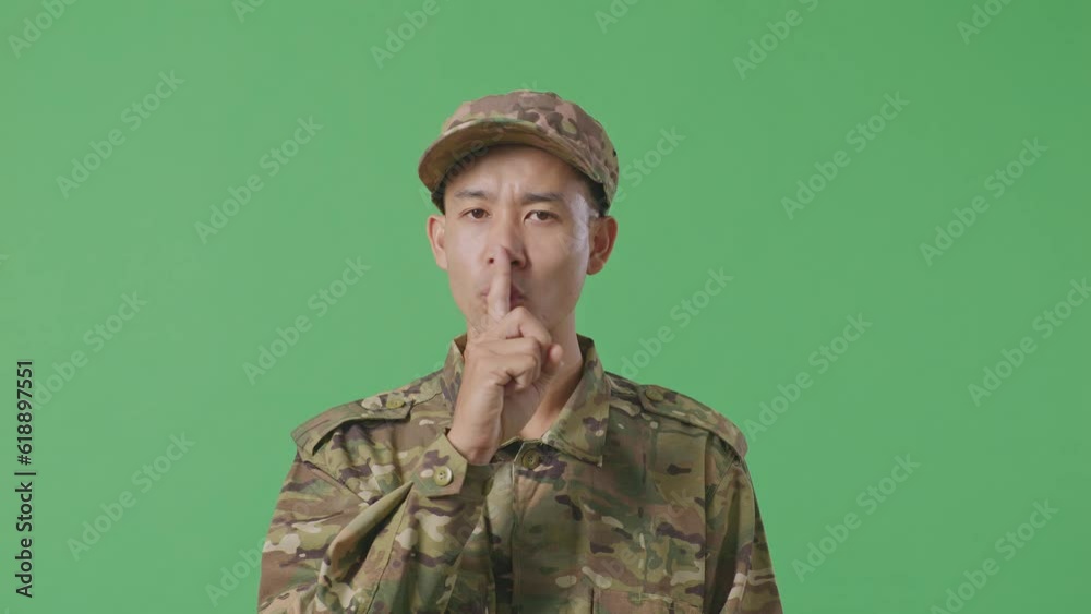 Close Up Of Asian Man Soldier Looking At Camera And Making Shh Gesture While Standing In The Green Screen Background Studio
