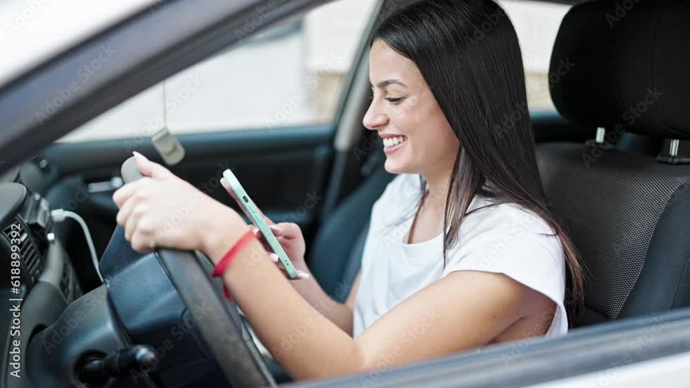 Young beautiful hispanic woman using smartphone sitting on car at street Young beautiful hispanic woman using smartphone sitting on car at street