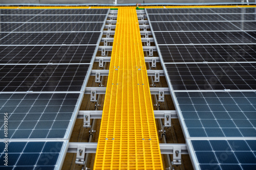 Close-up of Photovoltaic panels with yellow walk-way for maintenance on the rooftop of the building