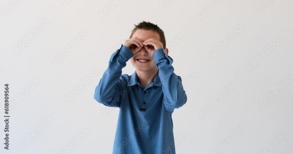 Imaginative Asian boy as he gazes into an imaginary pair of binoculars on a pristine white background. With an expression of wonder on his face, he peeks through his make-believe lenses. Imaginative Asian boy as he gazes into an imaginary pair of binoculars on a pristine white background. With an expression of wonder on his face, he peeks through his make-believe lenses.