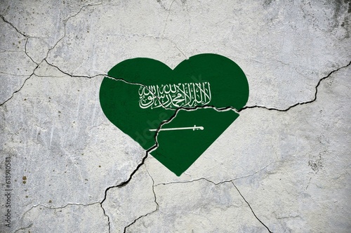 The symbol of the national flag of Saudi Arabia in the form of a heart on a cracked concrete wall.