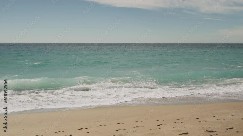 Slow motion clear blue waves with strong wind on a sandy empty beach in Cannes in spring Slow motion clear blue waves with strong wind on a sandy empty beach in Cannes in spring