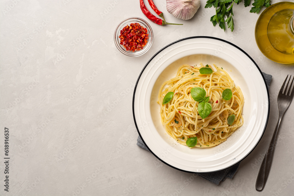 Spaghetti aglio e olio. Traditional Italian pasta with garlic, olive oil and chili peppers in plate on concrete background. Spaghetti aglio e olio. Traditional Italian pasta with garlic, olive oil and chili peppers in plate on concrete background.
