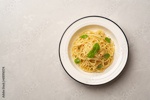 Spaghetti aglio e olio. Traditional Italian pasta with garlic, olive oil and chili peppers in plate on concrete background. photo