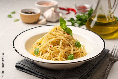 Spaghetti aglio e olio. Traditional Italian pasta with garlic, olive oil and chili peppers in plate on concrete background. photo