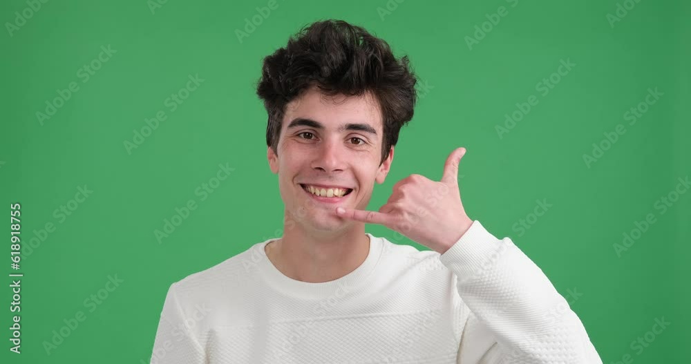 Friendly Caucasian man on a vibrant green background, expressing the call me gesture. With a bright smile, he curling his thumb and pinky finger while keeping the other three fingers upright. Friendly Caucasian man on a vibrant green background, expressing the call me gesture. With a bright smile, he curling his thumb and pinky finger while keeping the other three fingers upright.