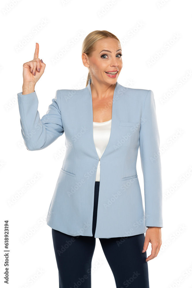 Middle aged happy senior business woman in reue jacket pointing up on white studio background Middle aged happy senior business woman in reue jacket pointing up on white studio background