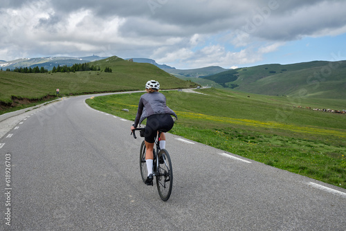 Woman riding on bicycle amidst mountains. Fit athlete wearing cycle wear and helmet. Sports motivation image. Bucegi Mountains