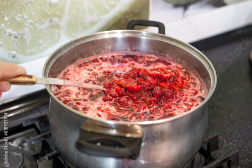 Seedless cherry jam is cooked in a large saucepan on the stove. Preservation of fruits and berries