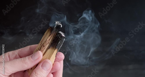 Holding Palo Santo in hands, person showing Mexican smudging wooden sticks, smoke slowly spreading, close up 4k footage, high quality relaxation video for meditation