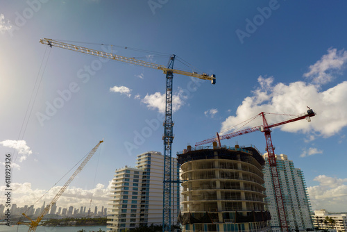 Aerial view of new developing residense in american urban area. Tower cranes at industrial construction site in Miami, Florida. Concept of housing growth in the USA