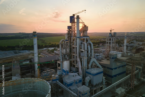 Cement plant with high factory structure and tower cranes at industrial production area. Manufacture, global industry and air pollution concept