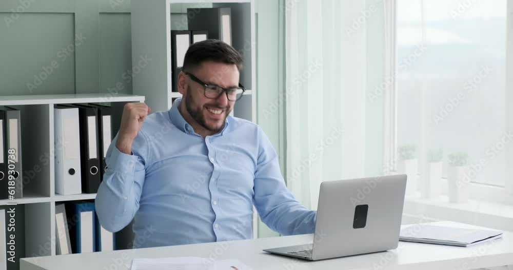 Caucasian businessman sitting at his desk in his office, working on his laptop. Suddenly sees something that makes him incredibly happy. Caucasian businessman sitting at his desk in his office, working on his laptop. Suddenly sees something that makes him incredibly happy.