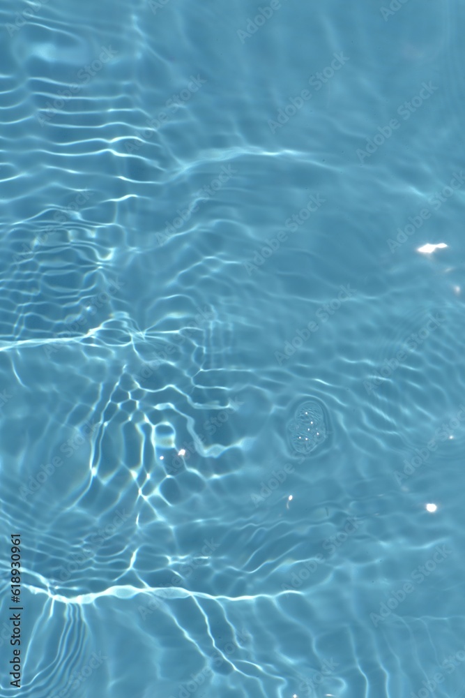 Blue water with ripples on the surface. Defocus blurred transparent blue colored clear calm water surface texture with splashes and bubbles. Water waves with shining pattern texture background.