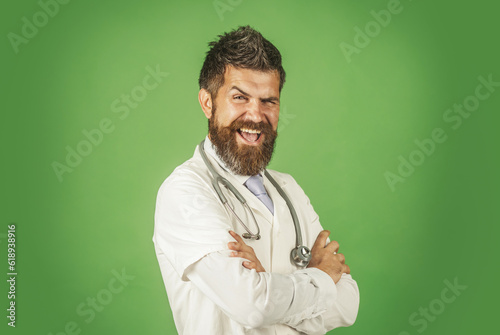 Happy doctor in medical gown with stethoscope on neck. Male physician in white medical robe with folded arms. Smiling doctor in workwear with crossed arms. Medicine, treatment and healthcare concept.