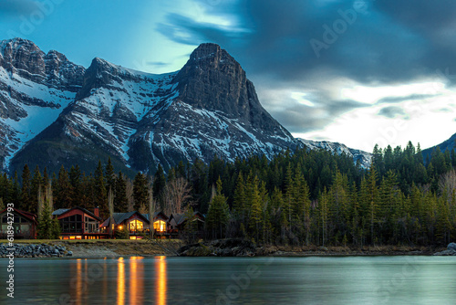 Wooden cabins in forest below mountain peak during night