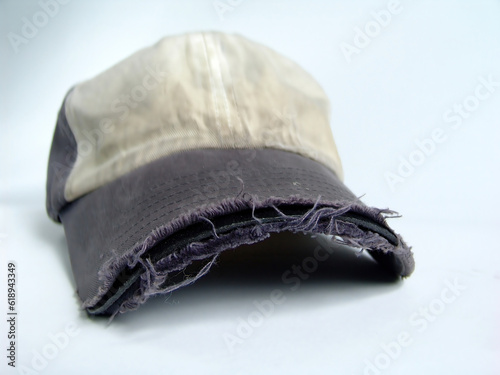 Old, worn and frayed baseball hat on solid background