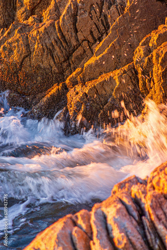 Waves crushing to a rock cliff during sunset