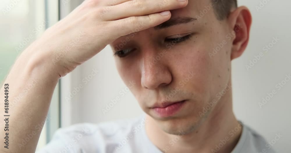 Caucasian Man sits on the windowsill, gazing into the distance with a heavy heart. His expression reflects the weight of his sorrows, as if he carries a burden within him. Caucasian Man sits on the windowsill, gazing into the distance with a heavy heart. His expression reflects the weight of his sorrows, as if he carries a burden within him.