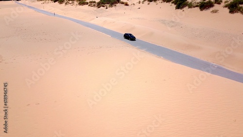 aerial view of a car driving on a road in a sandy dune landscape near Valdevaqueros with a pine forest in the background  Tarifa  Cadiz  Andalusia  Spain  fantastic landscape  tourism  travel