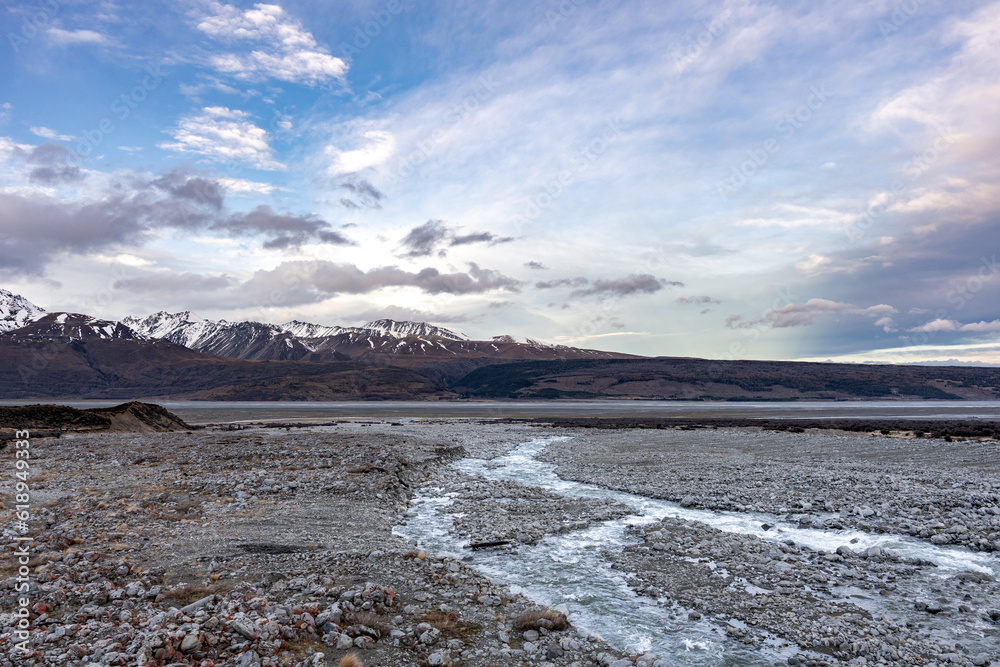 Scenic view at Mount Cook Road alongside Lake Pukaki with snow capped Southern Alps basking in the late winter evening light. Best road trip route in New Zealand South Island.