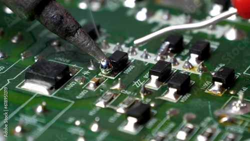 Close-up of repairman soldering on circuit board.
