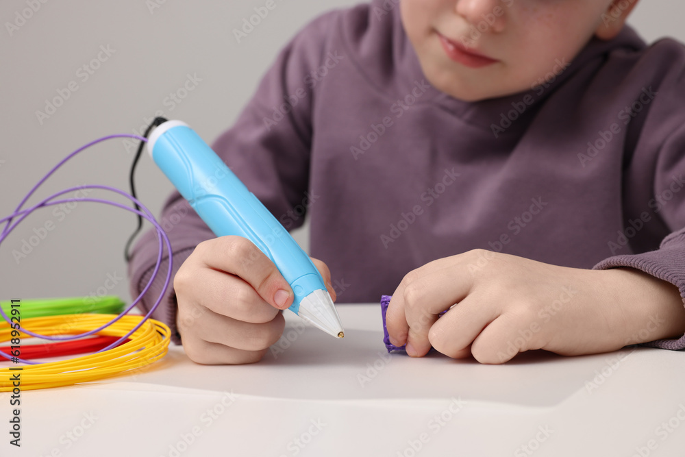 Boy drawing with stylish 3D pen at white table, closeup Boy drawing with stylish 3D pen at white table, closeup