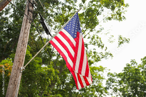 US flag waves proudly in front of an American home, representing the meaning and symbolism of patriotism, American holidays like July 4th and Memorial Day, and the pride of being an American