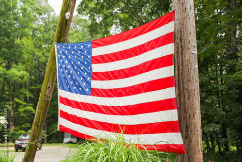 US flag waves proudly in front of an American home, representing the meaning and symbolism of patriotism, American holidays like July 4th and Memorial Day, and the pride of being an American