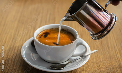 a cup of coffee that is being added cream