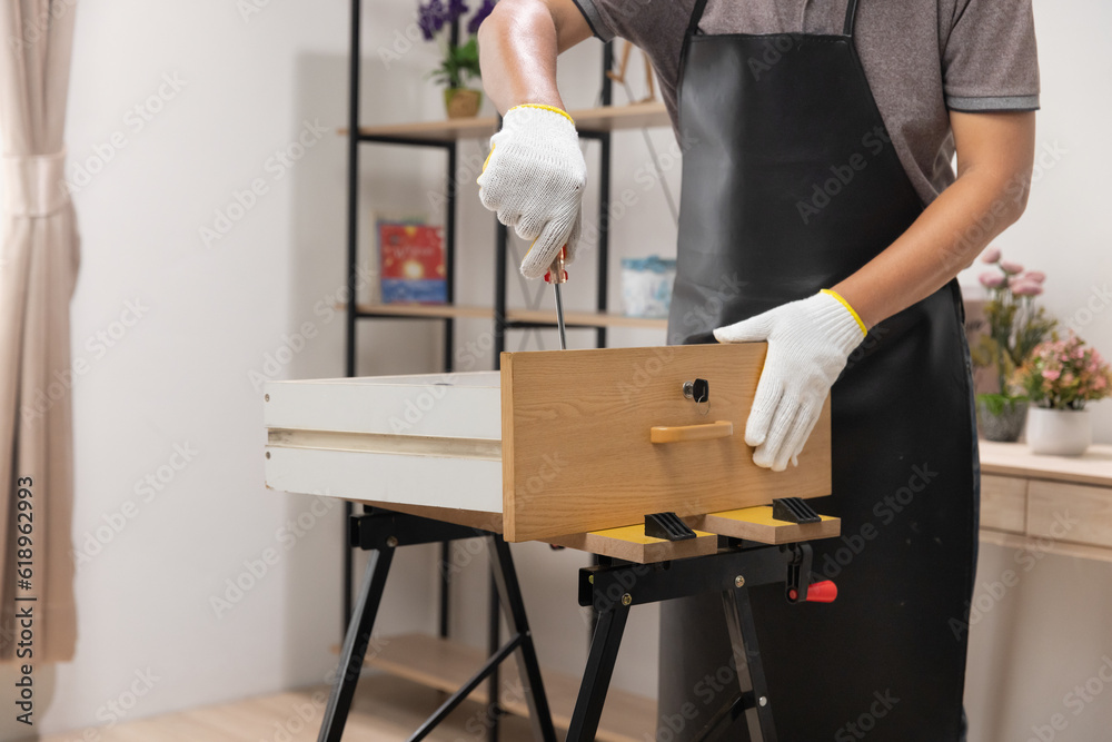 Worker repair wooden drawer of cabinet in living room.