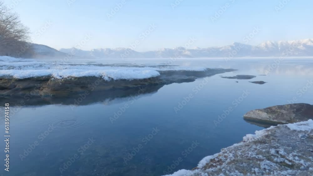 Morning mist blowing over shore of thermal lake water in frozen winter landscape Morning mist blowing over shore of thermal lake water in frozen winter landscape