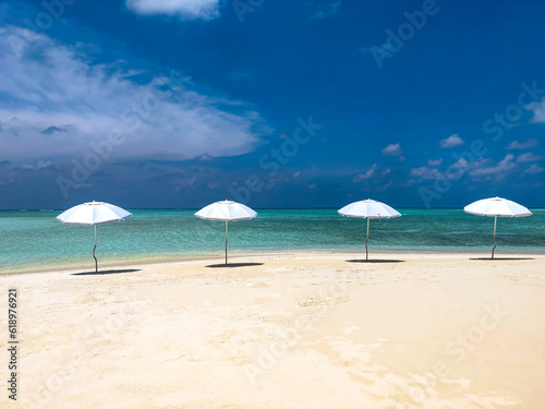  Summer tropical with white umbrella on the beach with blue sky background