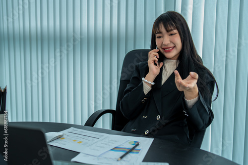 Happy businesswoman talking on the phone while analyzing weekly work schedule on her tablet